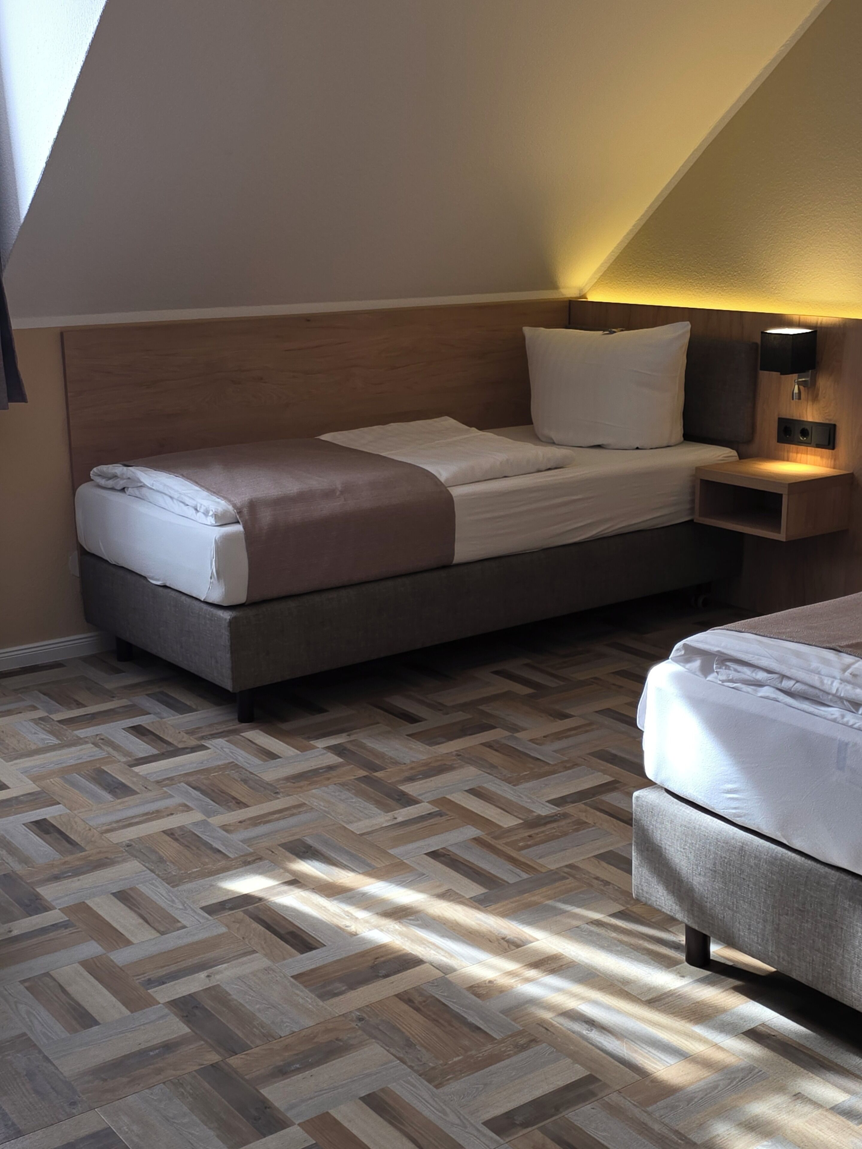 A bedroom with a bed, a nightstand, and a wall-mounted lamp.