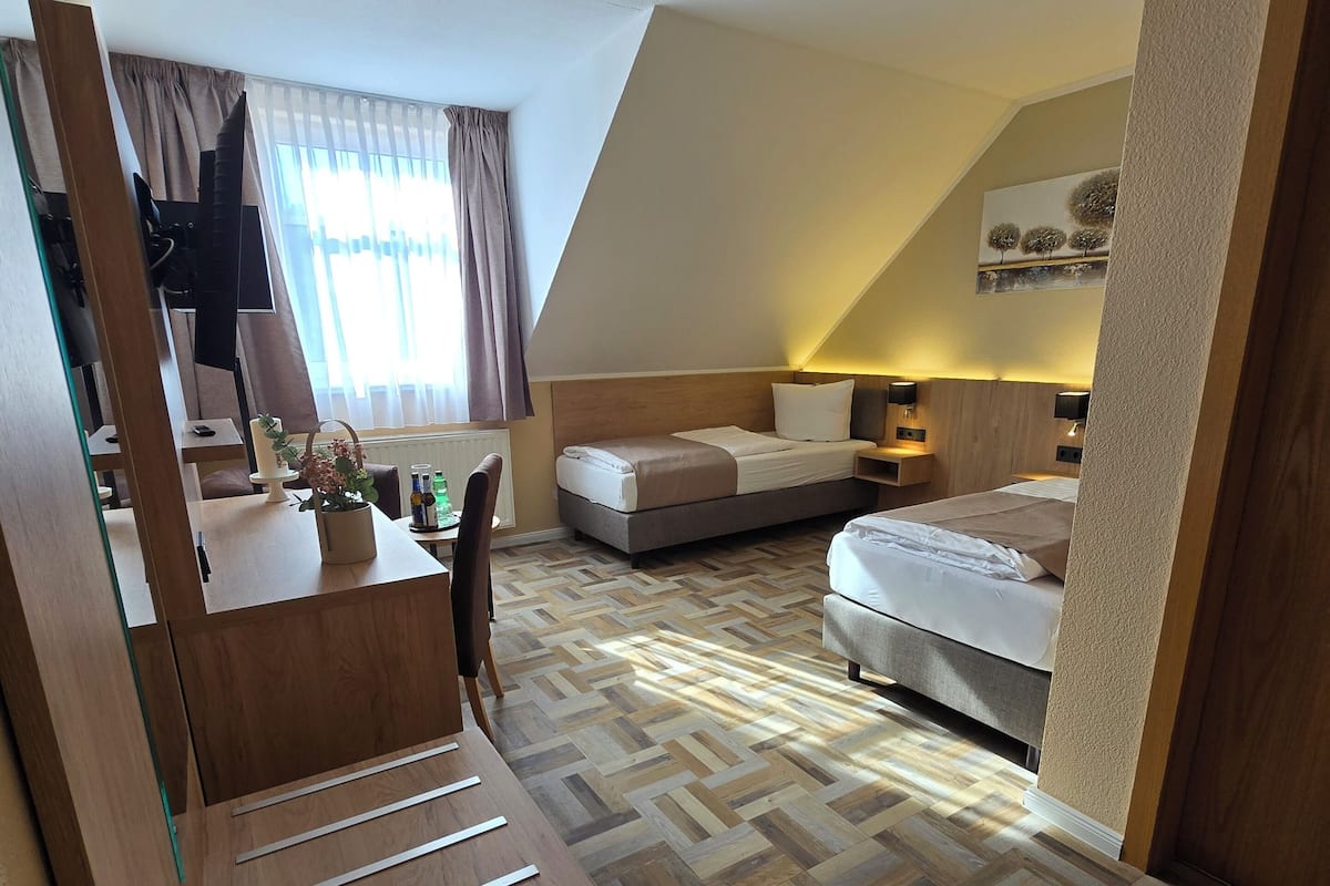 A hotel room with a wooden desk, a bed, a sofa, and a dining table.