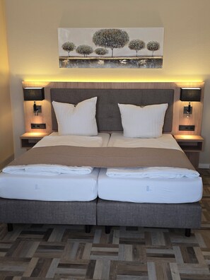 A double bed with a headboard, two bedside tables with lamps, and a painting above the bed. - Landgasthaus Zander (Blankenburg)