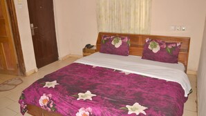 A bedroom with a bed, wooden headboard, and floral bedspread.