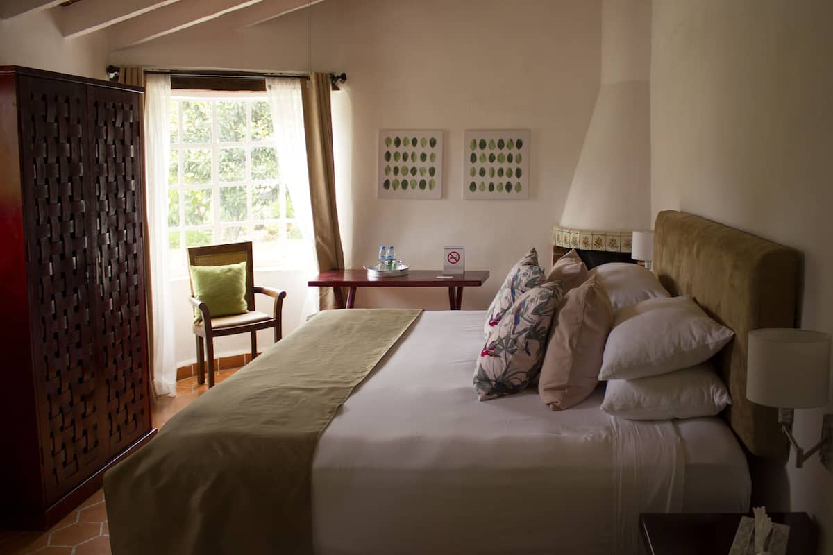 Una habitació d'hotel amb un llit, una cadira, una taula i una finestra.