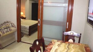 A room with a bed, a sofa, a table, and a chair. - Corina Hotel (Monrovia)