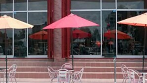 A building with large windows and outdoor seating with umbrellas. - Corina Hotel (Monrovia)
