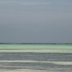 Aan een privéstrand, wit zand, ligstoelen, parasols
