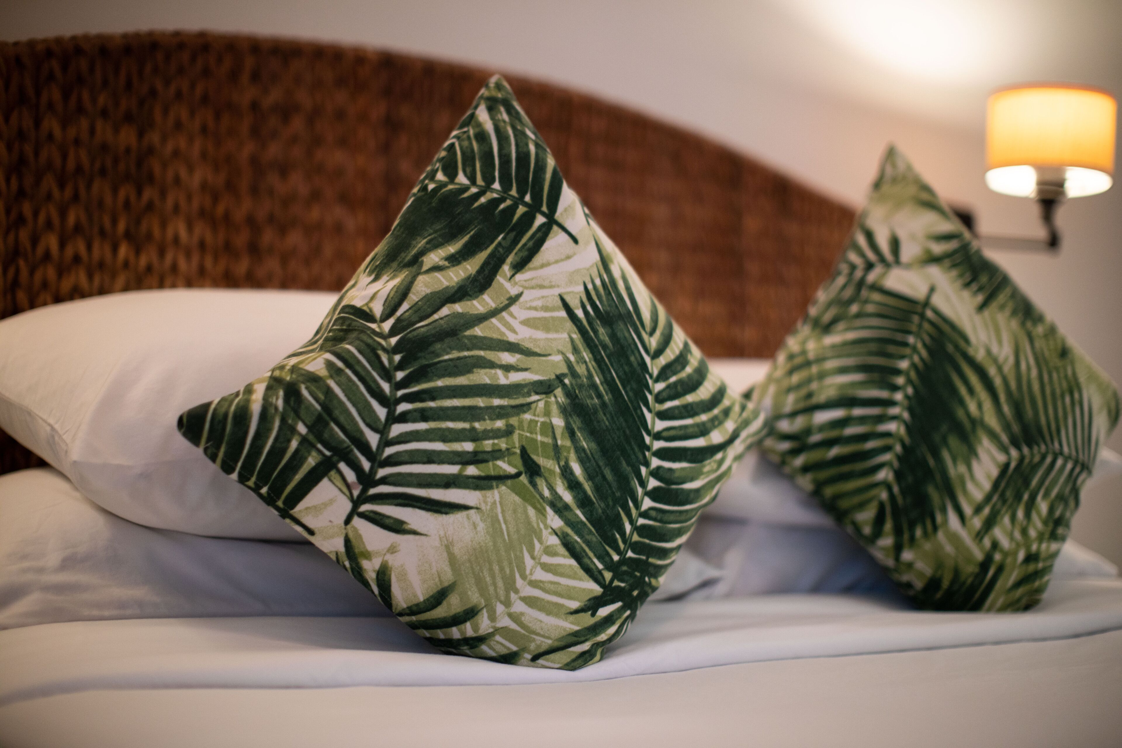 A bed with two pillows featuring a tropical leaf pattern.