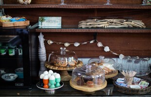 A bakery display with various pastries and desserts, including cakes and muffins, covered with glass domes.