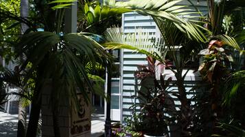 Un jardín con plantas en macetas, un sendero y un edificio con fachada blanca.