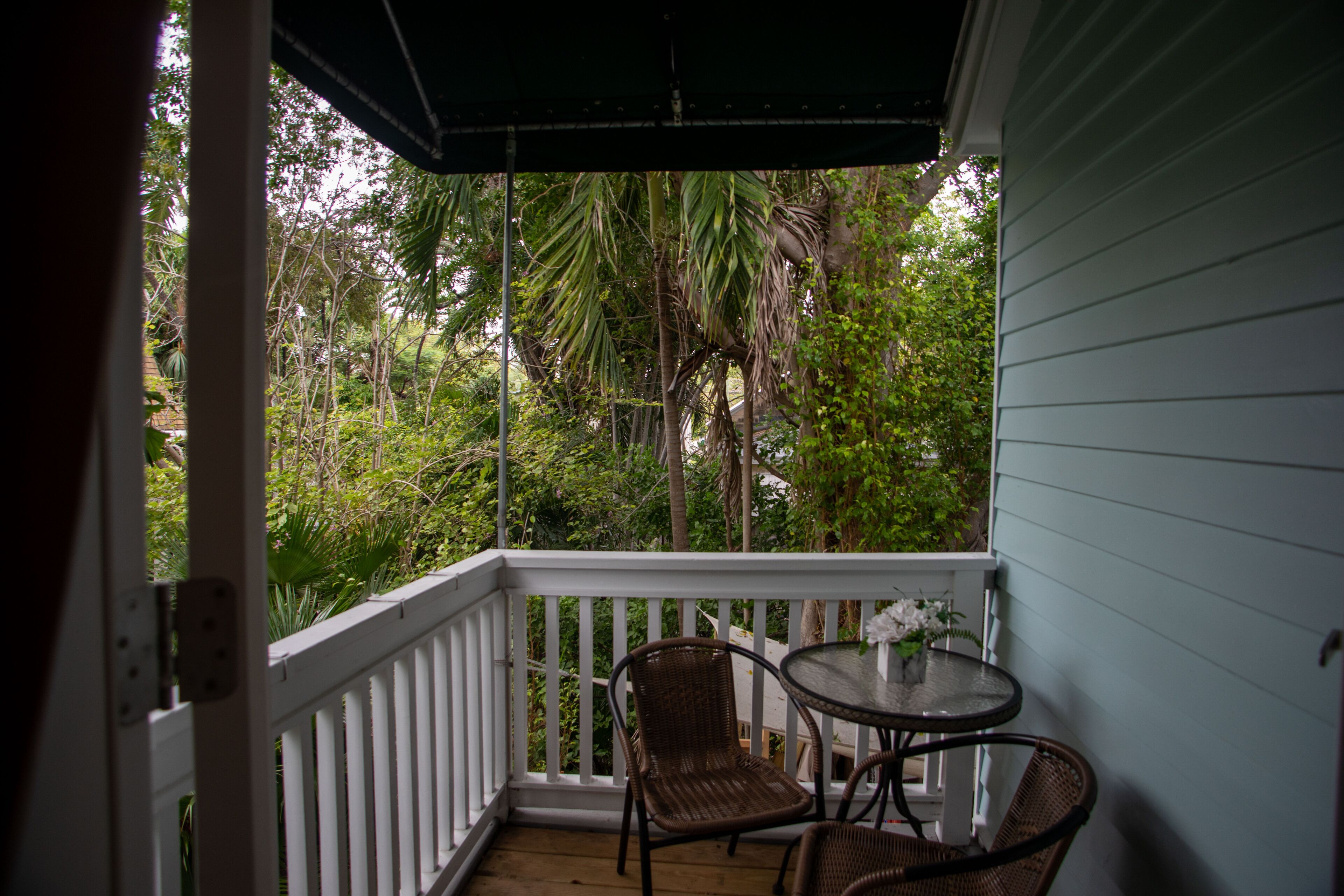 A covered porch with white railings, two wicker chairs, and a small table.