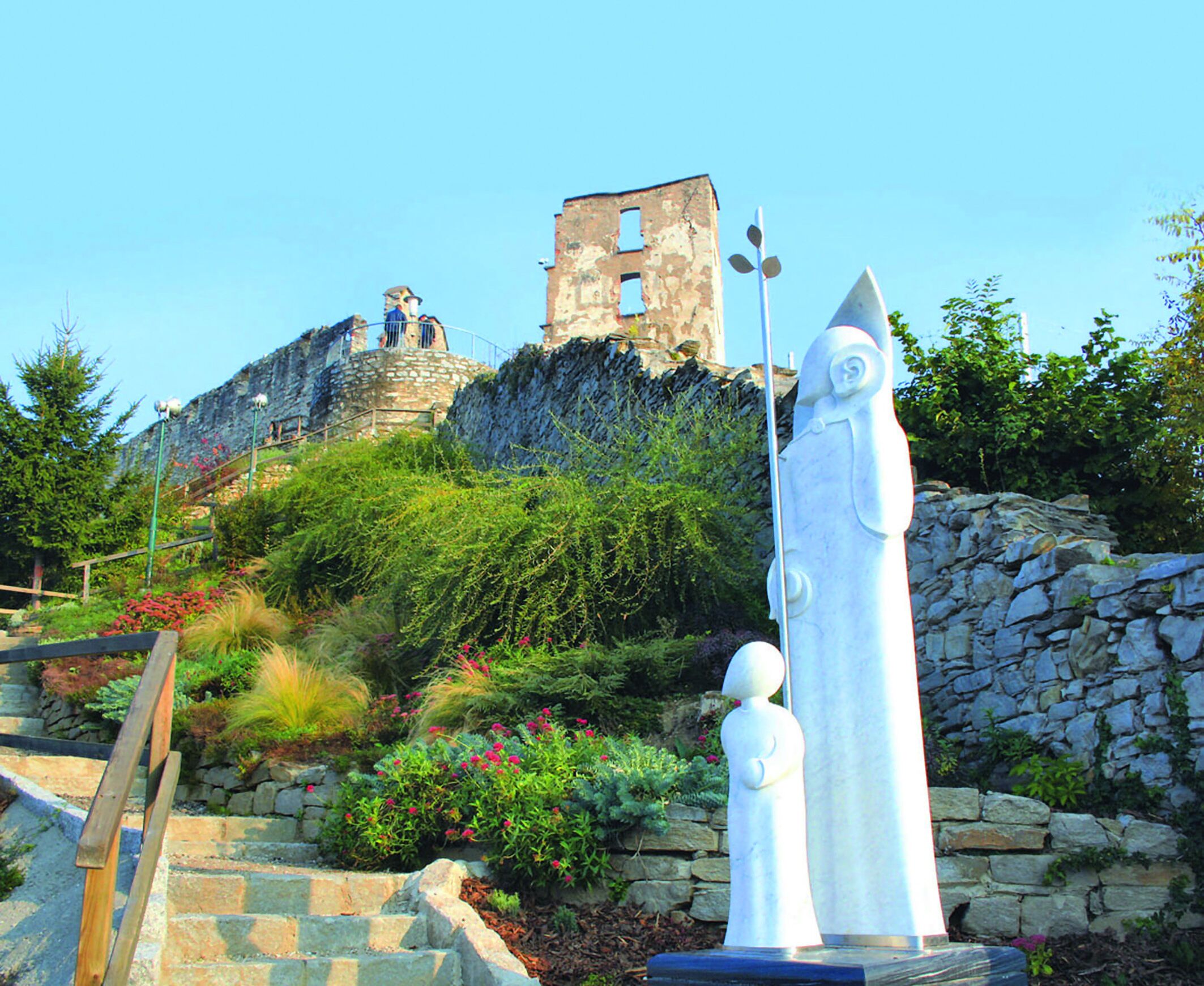 A stone staircase leading up to a castle-like structure with a statue in the foreground.