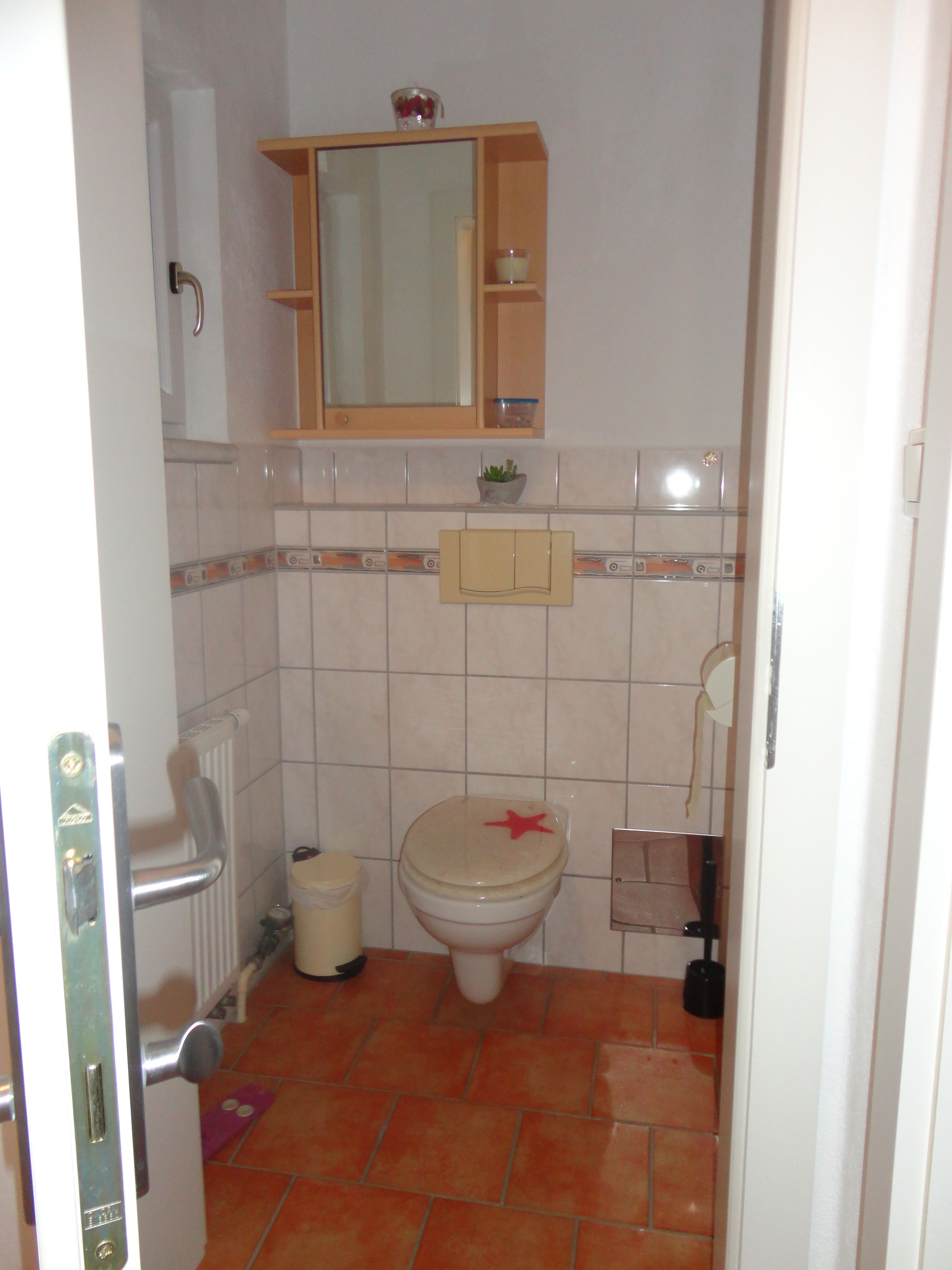 A small bathroom with a toilet, a sink, and a mirror above the mirror.