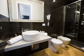 A modern bathroom with a large mirror, a round sink, a toilet, and a bidet. - Ara Suite (Rome)