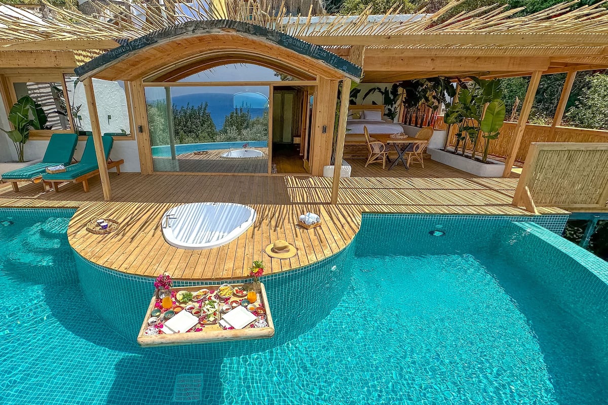 A pool area with a hot tub, lounge chairs, and a dining setup with a buffet.