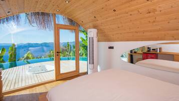 Ein Schlafzimmer mit Holzbalkendecke, einem großen Fenster mit Bergblick, einem Bett und einer kleinen Schreibtischzeile.