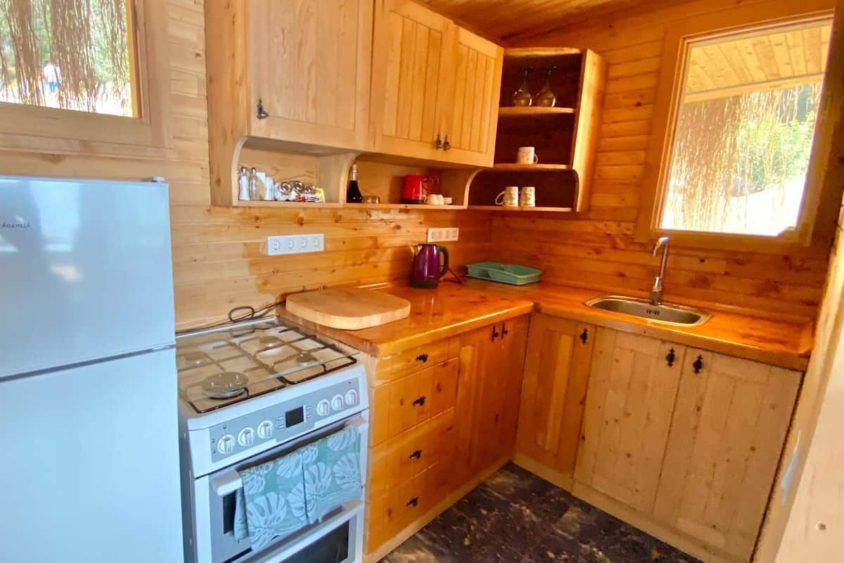 A compact kitchen with wooden cabinets, a white refrigerator, a gas stove, and a sink.