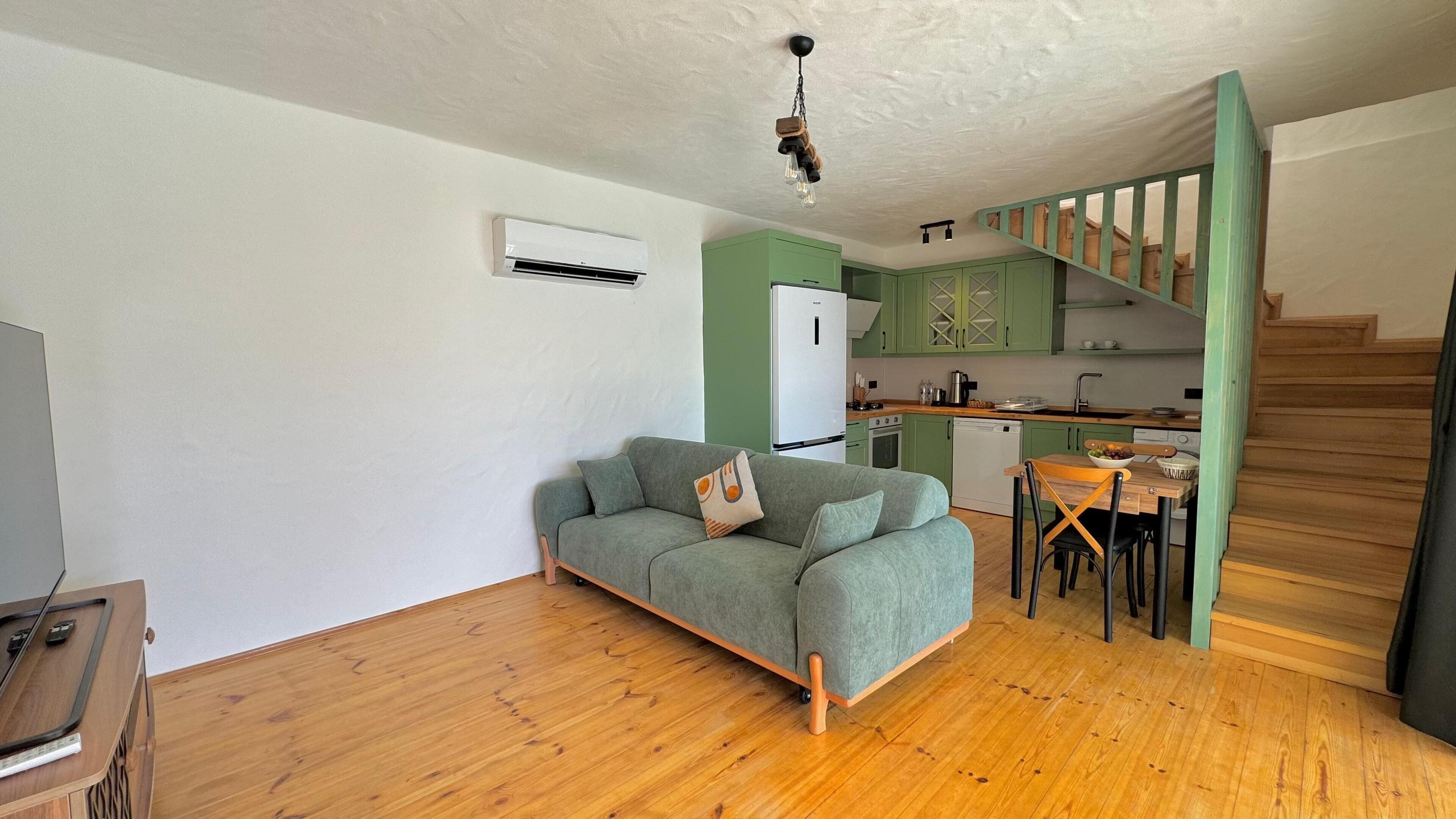 Un espacio habitable compacto con sofá, mesa de comedor y zona de cocina.