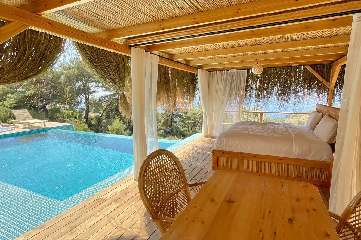 A wooden deck with a pool, a bed, and a table.