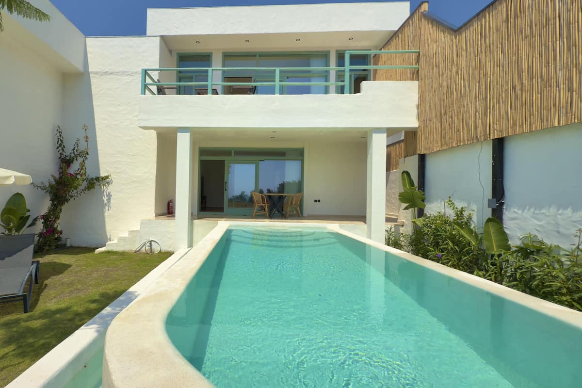 A modern house with a swimming pool, a balcony, and a garden.