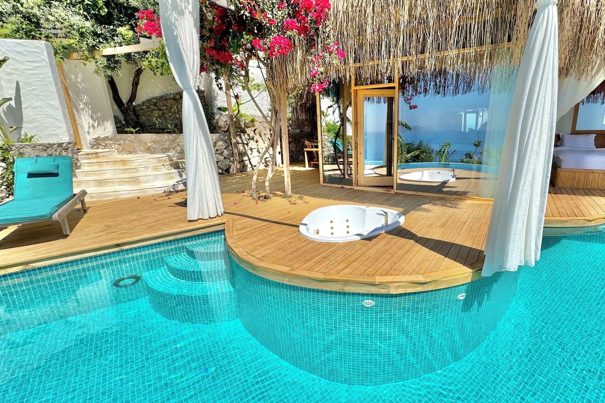 A pool area with a hot tub, lounge chairs, and a wooden deck.