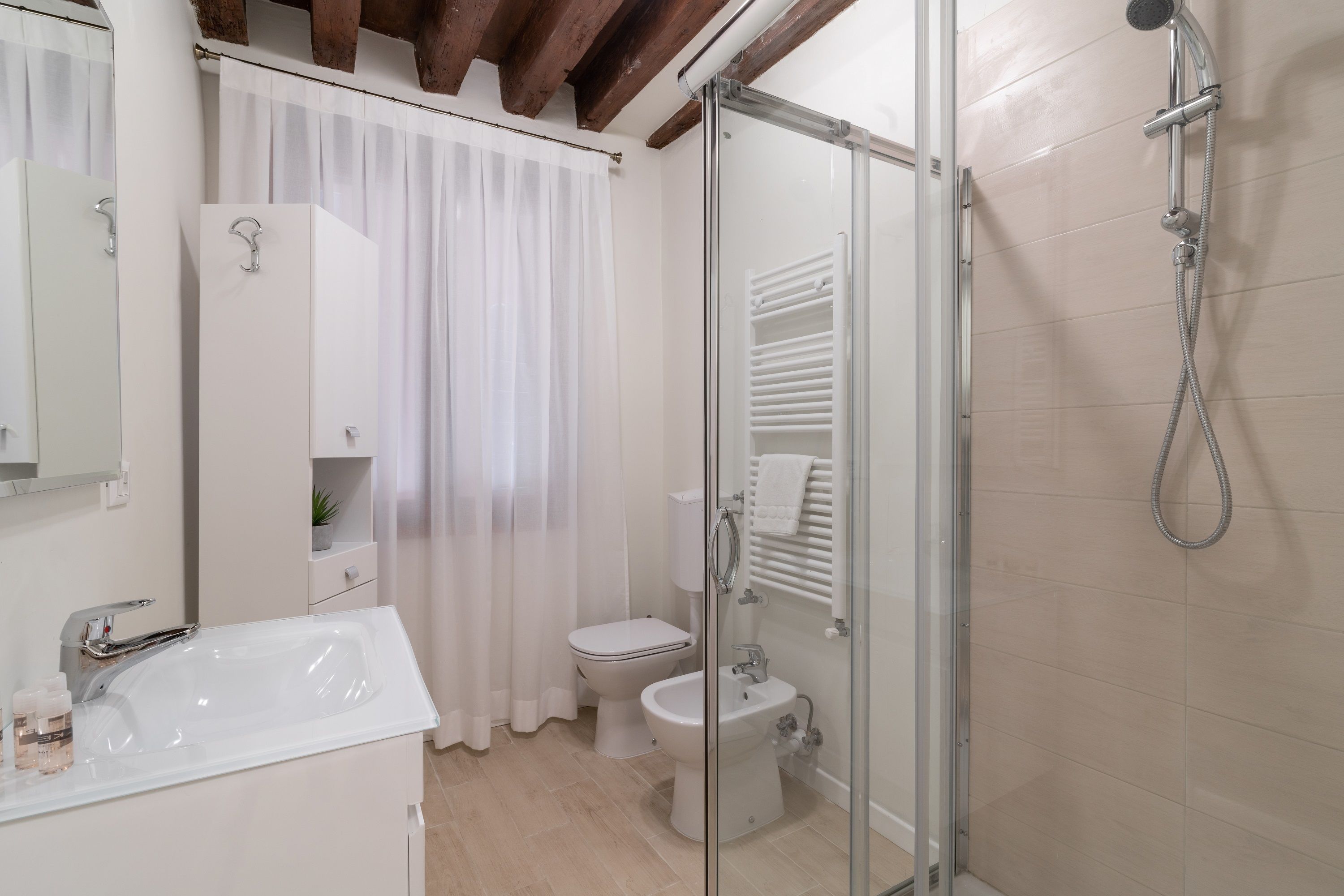 A modern bathroom with a glass shower enclosure, a white sink, and a toilet.