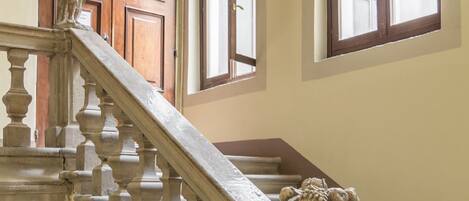 A grand staircase with ornate balusters and a stone balustrade, leading to a wooden door with a decorative arch above it.