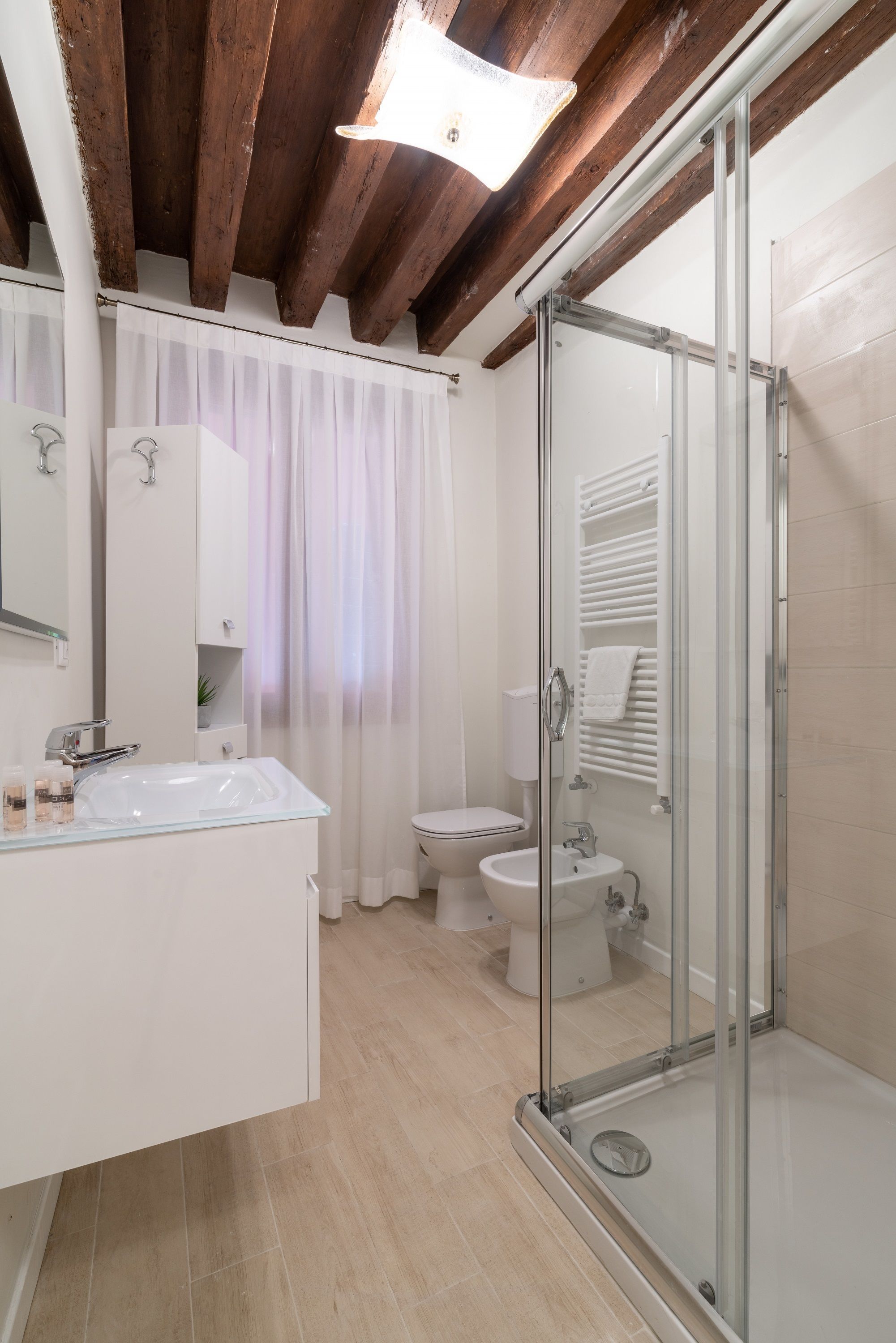 A modern bathroom with a glass shower enclosure, a white sink, and a toilet.