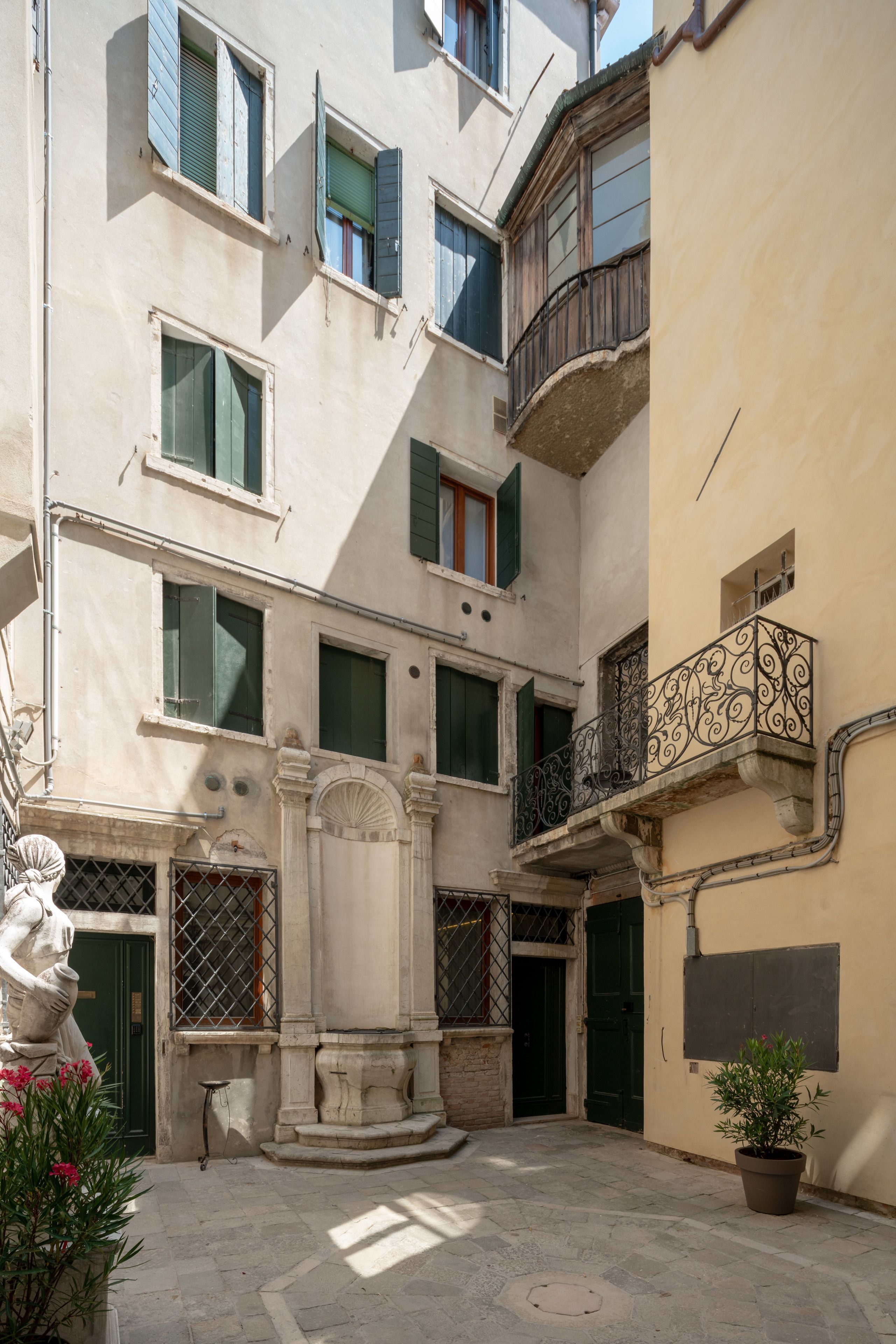 A courtyard with a statue, a fountain, and a potted plant.