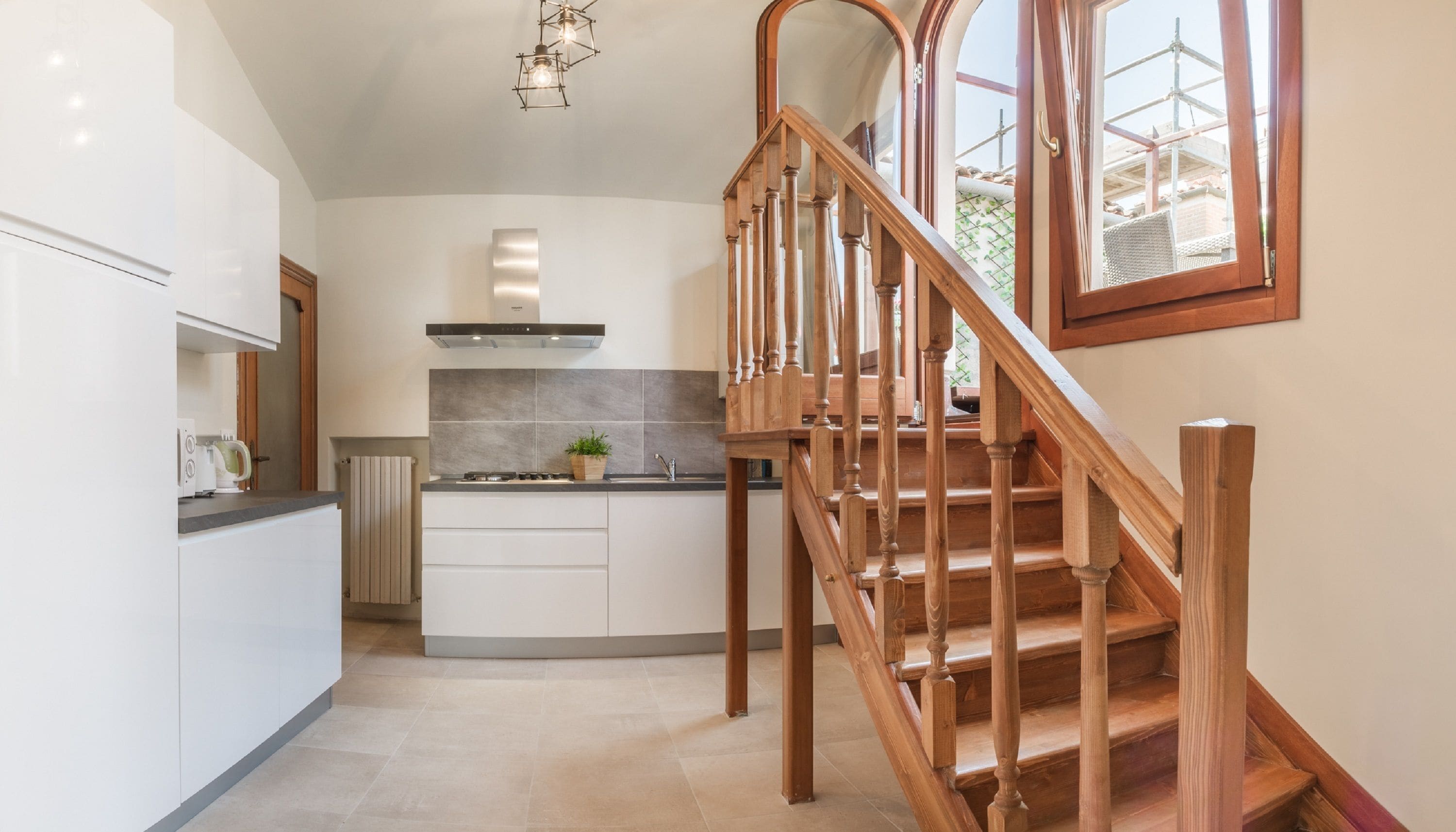 Una cucina moderna con una scala in legno che conduce a un balcone.