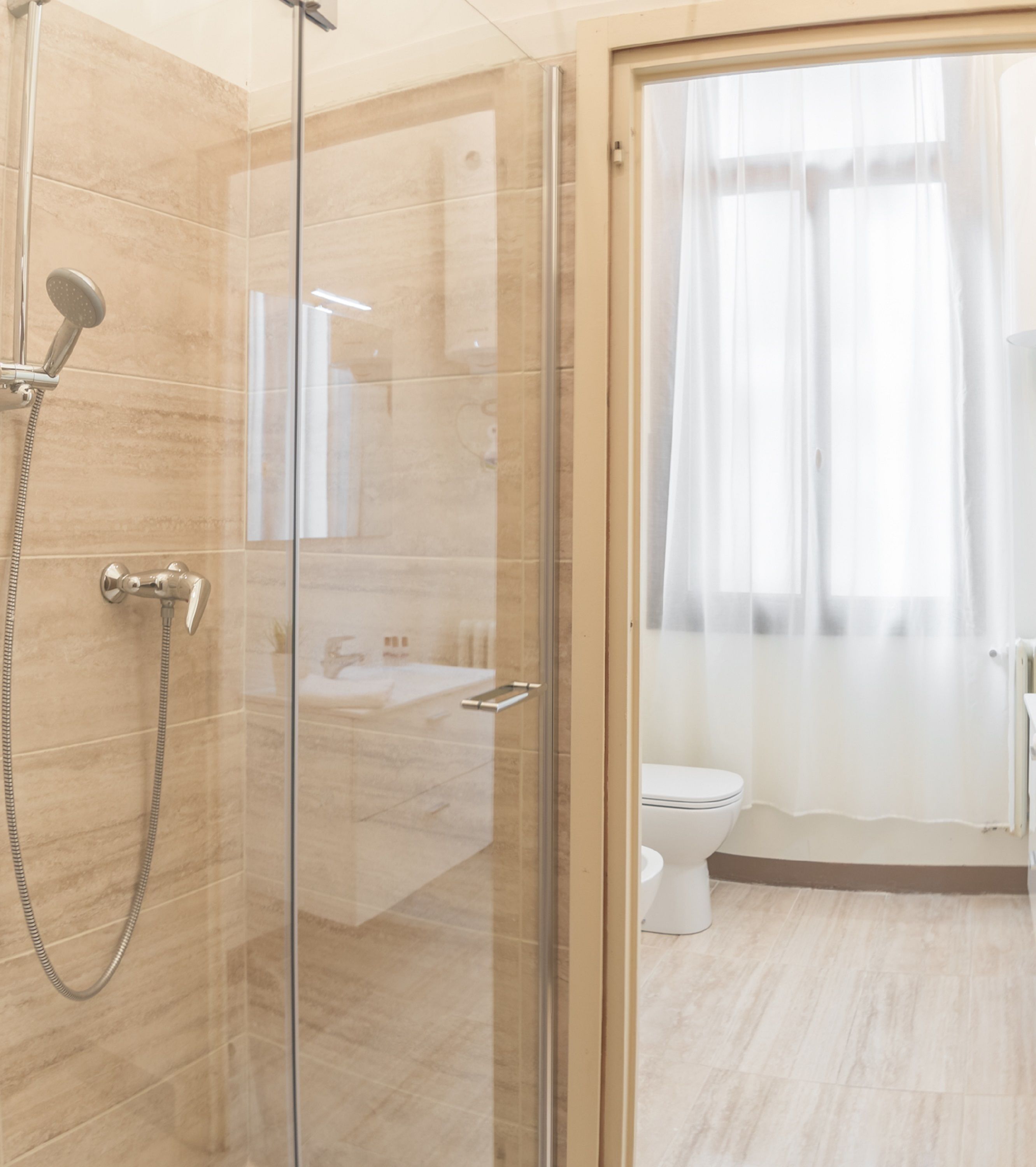A modern bathroom with a glass-enclosed shower, a toilet, and a sink.