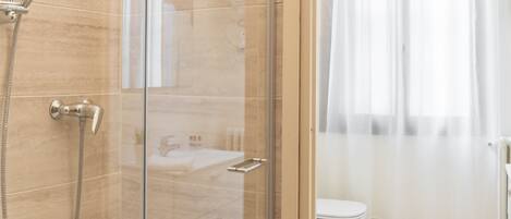 A modern bathroom with a glass-enclosed shower, a toilet, and a sink.