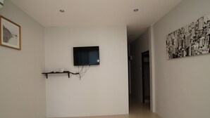 A room with a flat-screen TV mounted on the wall, a framed picture on the left, and a black and white abstract painting on the right. - Baan Samart 1 Pool Villa Hua Hin (Hua Hin)