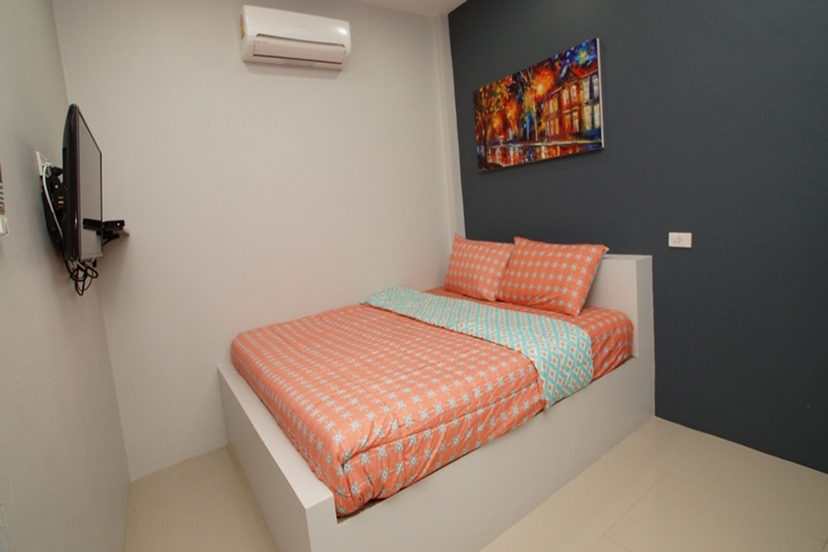 Un dormitorio con cama, aire acondicionado, un cuadro y televisor en la pared.