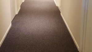 A long, narrow hallway with carpeted floors, white walls, and doors on both sides. - Motell Trafikanten (Bygdea)