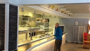 A modern kitchen area with a counter and a person standing at it. - Motell Trafikanten (Bygdea)