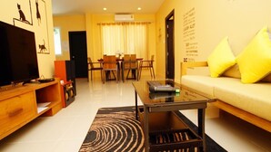 A living room with a TV, sofa, coffee table, and dining area with chairs and a table. - Baan Tachcha Pool Villa Hua Hin (Hua Hin)