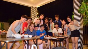 A group of people gathered around a barbecue grill outdoors at night. - Baan Tachcha Pool Villa Hua Hin (Hua Hin)