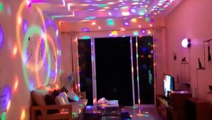 A living room with a sofa, a coffee table, and a TV. There are colorful lights on the ceiling and walls. - Baan Tachcha Pool Villa Hua Hin (Hua Hin)
