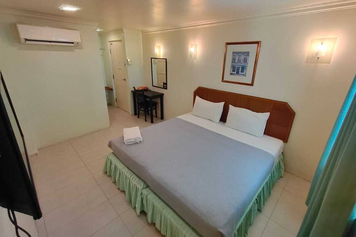 Habitación de hotel con cama, escritorio, silla y espejo.