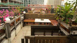 A rooftop restaurant with wooden benches and tables, surrounded by potted plants and flowers. - Johan Travellers Lodge (Malacca City)