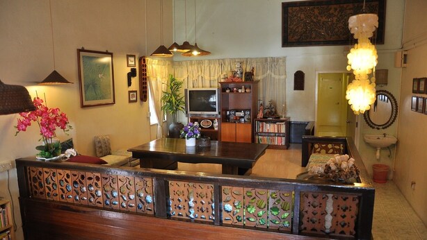 A cozy living room with a wooden bench, a TV, and a bookshelf. - Johan Travellers Lodge (Malacca City)