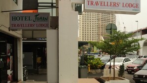 The exterior of Hotel Johan Travellers' Lodge with a clear entrance, a stone pillar, and a parking area with cars. - Johan Travellers Lodge (Malacca City)