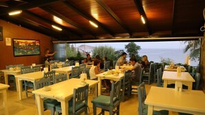 A restaurant with outdoor seating overlooking a scenic view. Tables are arranged in rows with chairs. - Manolya Hotel (Bodrum)