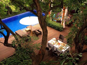 A poolside area with a wooden deck, a dining table set for two, and a small pool with a blue border. - Baan Klang Wiang Boutique Hotel Chiang Mai (Chiang Mai)