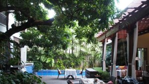 A covered outdoor dining area with tables and chairs, surrounded by lush greenery and a pool in the background. - Baan Klang Wiang Boutique Hotel Chiang Mai (Chiang Mai)
