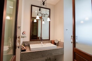 A bathroom with a white sink, a mirror, and a wall-mounted light fixture. - Baan Klang Wiang Boutique Hotel Chiang Mai (Chiang Mai)