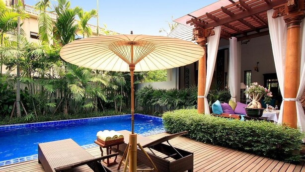 A wooden deck with a pool, lounge chairs, and an umbrella. - Baan Klang Wiang Boutique Hotel Chiang Mai (Chiang Mai)