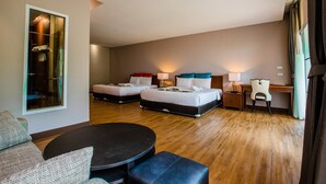 Une chambre d’hôtel avec deux lits, un bureau, une chaise, une table ronde et un canapé.