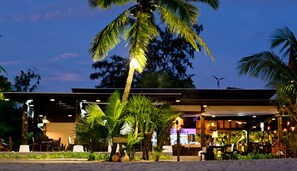 A beachfront restaurant with outdoor seating, palm trees, and a modern building structure. - C&N Kho Khao Beach Resort (Takua Pa)