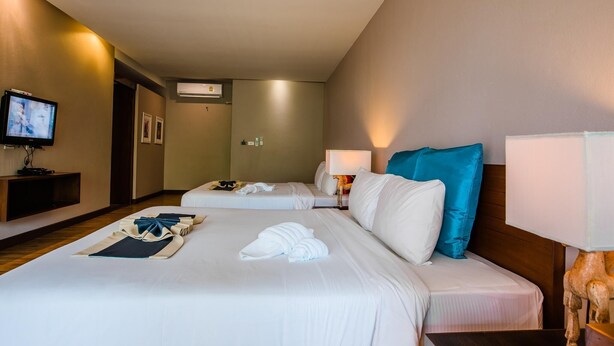 Une chambre d’hôtel avec deux lits, une télévision, un bureau et une lampe.