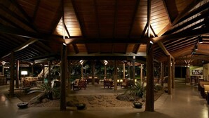 An indoor covered area with wooden beams, seating arrangements, and a central water feature. - Hotel Sigiriya (Dambulla)
