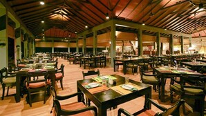 A large dining hall with multiple tables and chairs, high ceilings with exposed beams, and a warm lighting ambiance. - Hotel Sigiriya (Dambulla)